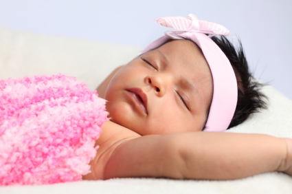a sleeping newborn baby wearing a pink bow